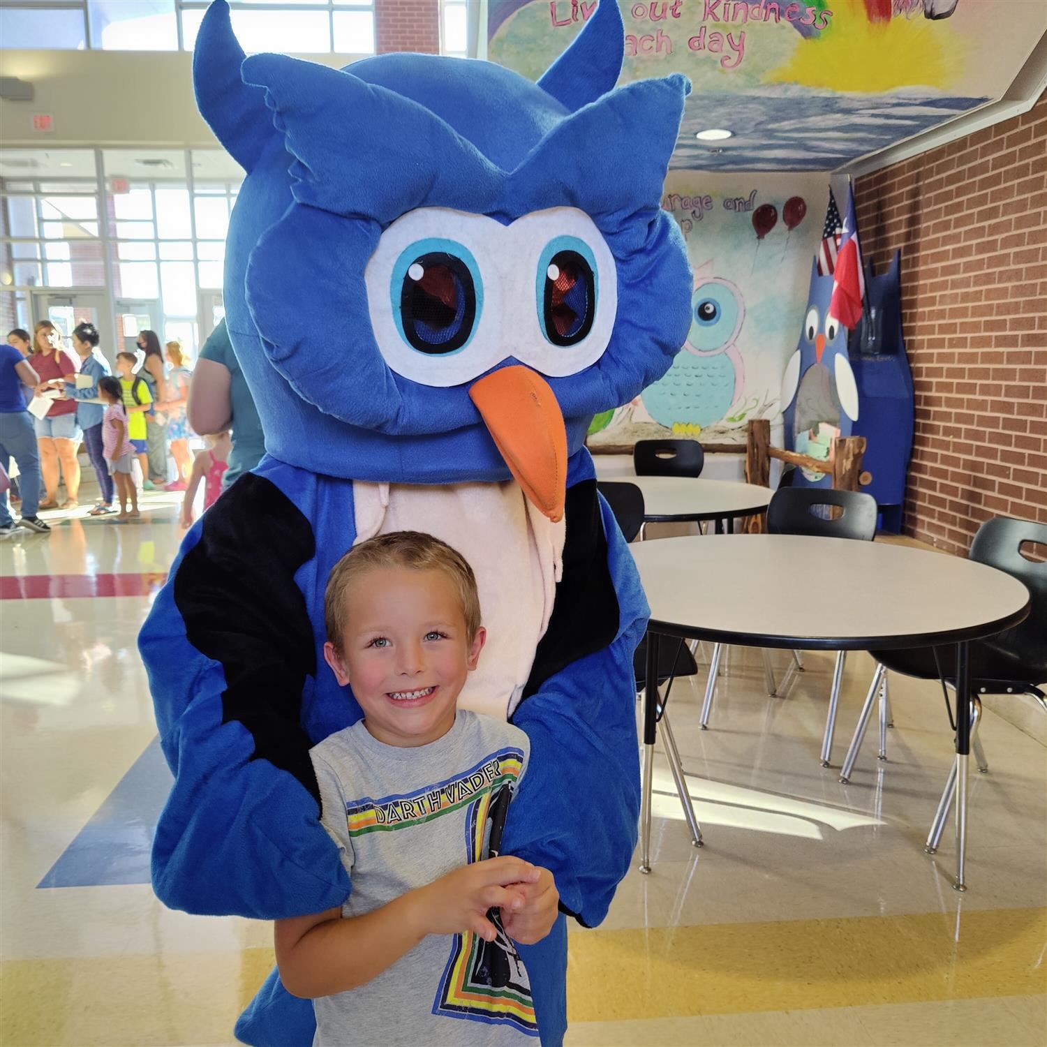 student poses with Ollie the Owl, the LPE mascot